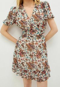 Floral wrap dress in lightweight fabric, featuring a V-neckline, puff sleeves, and ruffled hem. Colors include cream, brown, pink, and blue.