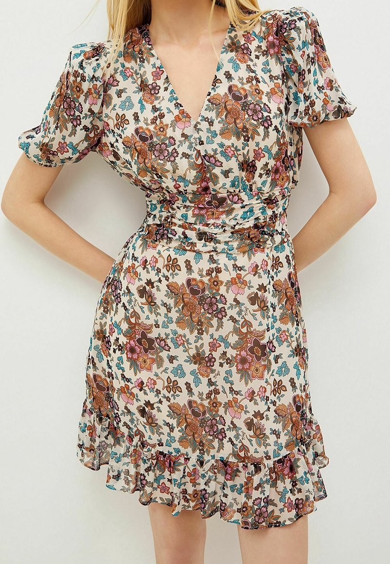 Floral wrap dress in lightweight fabric, featuring a V-neckline, puff sleeves, and ruffled hem. Colors include cream, brown, pink, and blue.