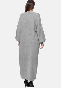 Abito grigio lungo a maglia, caratterizzato da una vestibilità morbida, maniche oversized e un motivo testurizzato. L'abito arriva fino alle caviglie.