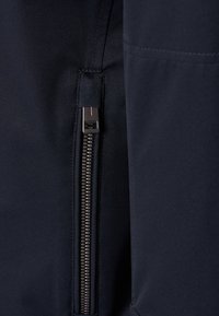 Mörkblått textil med en slät yta, med en framträdande dragkedja på vänster sida och ett robust dragkedjehandtag med kontrasterande detaljer.