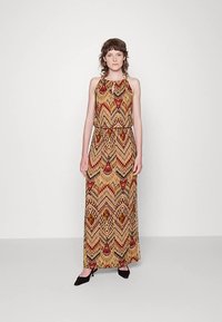 Maxikleid mit Neckholder-Design, versehen mit einem mehrfarbigen, geometrischen Muster in Erdtönen. Glatter Stoff, lockere Passform, knöchellang.