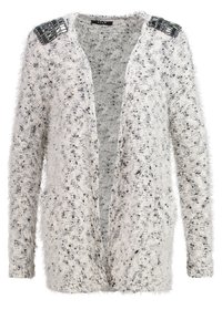 Vit fluffig cardigan med lös passform och texturerat mönster. Har glimmande svarta och silverfärgade axeldekorationer, öppet framdesign.