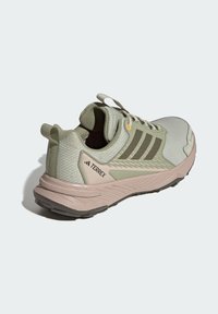 Lichtgroene sportschoen met een gestructureerd mesh bovenwerk, grijze accenten, beige zool en drie donkere strepen. Voorzien van een trekhaakje en veters.