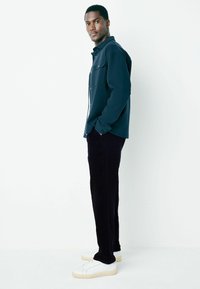 Navy button-up shirt, dark corduroy pants, white sneakers. Smooth texture, tailored fit, and no prominent patterns or accents.