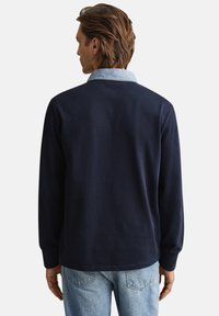 Donkerblauw overhemd met lange mouwen en een licht denim kraag, zachte textuur en een casual pasvorm. Heeft een rechte snit aan de zoom en geen zichtbare details.