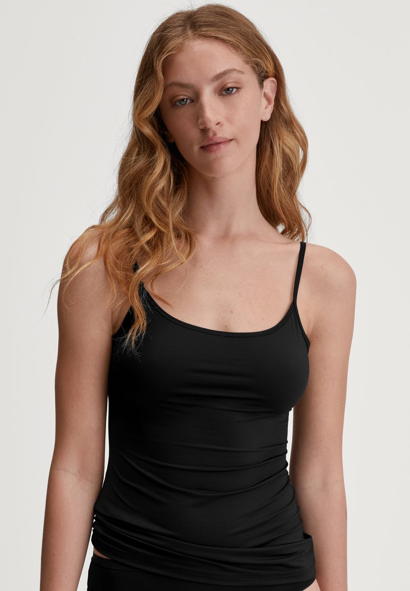 Zwarte tanktop met dunne bandjes, gemaakt van zachte, rekbare stof. Heeft een aansluitend ontwerp en een gladde textuur.
