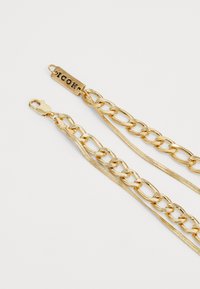 Gold chain with interlocking links and a flat tag engraved with "ICON." Features a lobster clasp and smooth, shiny texture.