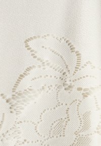 Tessuto bianco con intricati motivi floreali ritagliati su uno sfondo testurizzato, che mette in risalto i delicati dettagli del design.