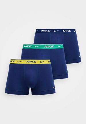 Tre boxer di Nike blu navy con elastici in vita colorati in giallo, verde e blu navy, ciascuno con il logo Nike e lo swoosh.