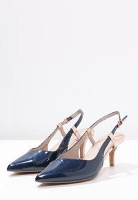 Modré lakované slingback boty s špičatou špičkou a 5 cm podpatkem. Mají růžový řemínek kolem kotníku a texturovaný vnitřek.