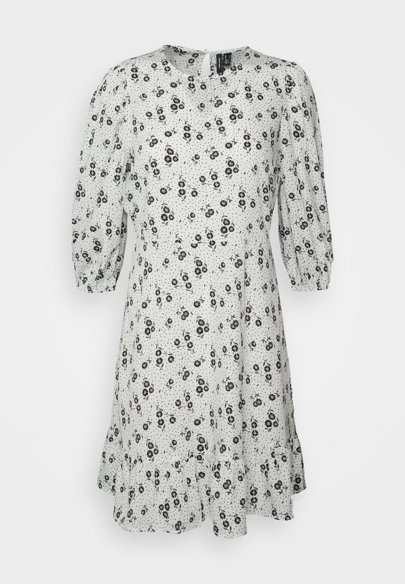Vestido de estampado floral em branco com padrões de flores pretas. Apresenta mangas bufantes, um decote redondo e uma bainha com volantes. Feito de tecido leve.