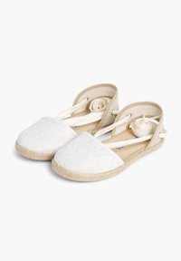Valged pitsilised espadrillid tekstuuriga pealispinnaga, ümarate varvastega ja kootud jute tallaga. Omavad beeže pahkluustrappe ja pehmet sisetald.