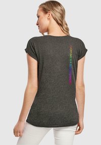 Graues T-Shirt mit kurz ausgefallenen Ärmeln, das auf der Rückseite mehrfarbigen Text trägt, der "JEDER TAG IST EIN NEUER BEGINN" liest. Glatte Textur.
