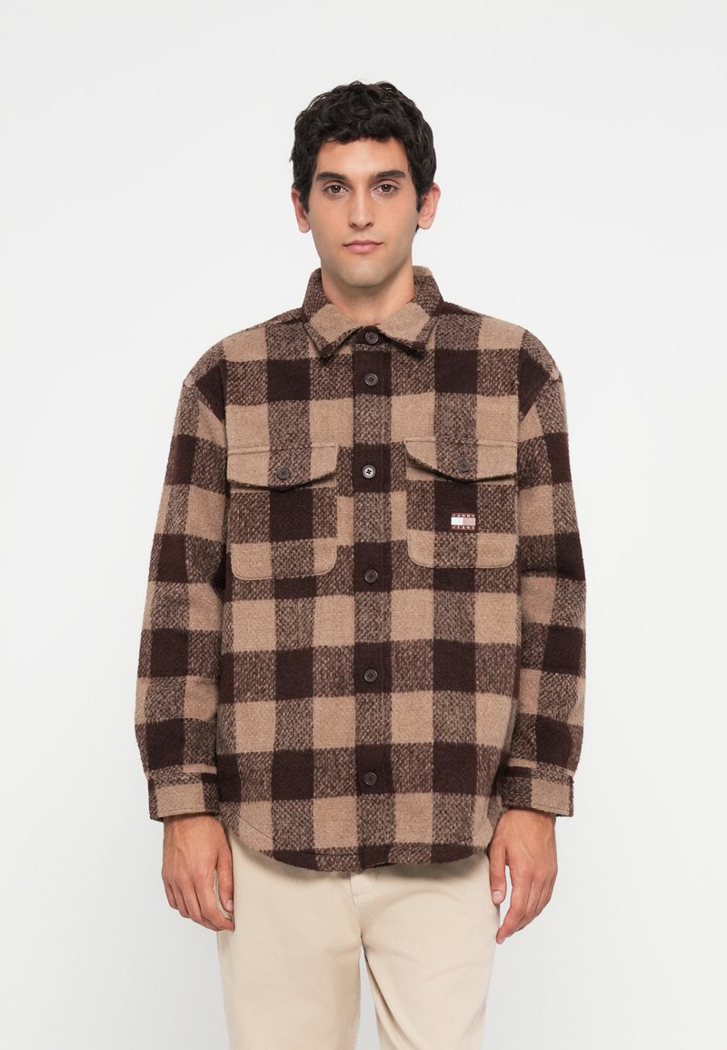 Bruin en beige geruite flanellen shirt met een knoopsluiting aan de voorkant, twee borstzakken en een label aan de linkerkant. Zachte textuur met een losse pasvorm.