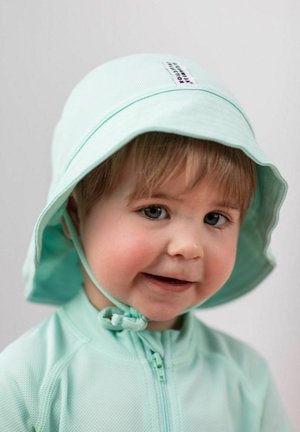 Mint green bucket hat with a rounded brim and chin strap, made of textured fabric; worn with a matching zip-up top.