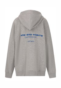 Grijze hoodie met ribgebreide manchetten en zoom. Heeft blauwe tekst op de achterkant: "NEW BAD HABITS" en "LES' ARCS." Zachte, gestructureerde stof.