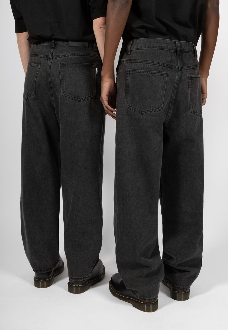 Svarta denimjeans med vida ben och hög midja, två bakfickor och synlig sömnad. Matchas med svarta skor.