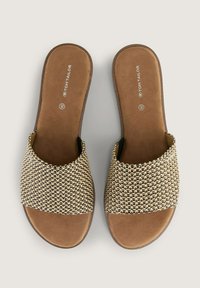 Sandali beige con tomaia intrecciata e sagomata in nero. Design flat con suola liscia e imbottita e punta aperta.
