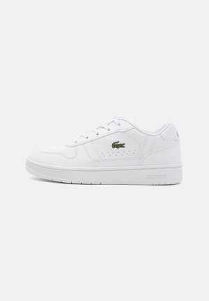 Hvit sneakers med en glatt læroverdel, perforert sidesøm og grønn Lacoste-logo. Har en tykk yttersåle og snøring.