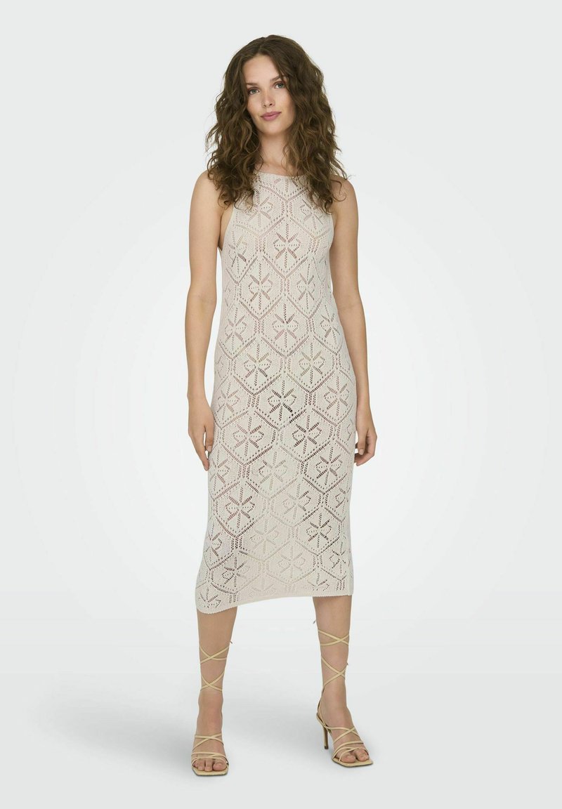 Abito midi in maglina color beige chiaro con ritagli geometrici e silhouette aderente. Presenta un collo rotondo e un design senza maniche.