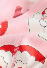 Vaaleanpunainen kangas esittelee Santa Claus -kuvia sisältävän kuvion. Korostusvärit ovat punaisia ja valkoisia, ja näkyvissä on ompeluyksityiskohtia.
