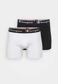 Two pairs of men's boxer briefs. One is white, the other is black. Both have a black elastic waistband with "Champion" logo in white and red.
