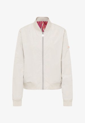 Lichtbeige bomberjack met ritssluiting aan de voorkant, geribbelde kraag en manchetten, en een rode en oranje patroonvoering aan de binnenkant.