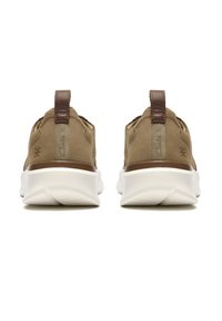 Par de zapatillas marrones sin cordones con suelas blancas gruesas vistas desde atrás, con lengüetas para tirar y detalles de costura.