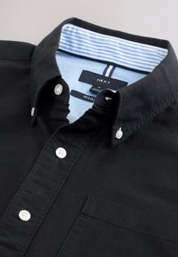 Camicia nera con bottoni e colletto. Presenta un colletto interno a righe azzurre e una singola tasca frontale. Realizzata in cotone.