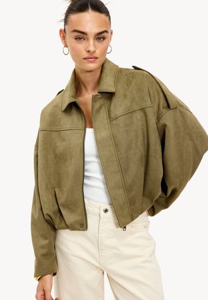 Olijfgroene suède jas met een cropped ontwerp, oversized mouwen en een ingesneden kraag. Voorzien van een ritssluiting en subtiele stikdetails.