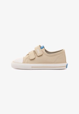 Chaussure en toile beige avec un bout en caoutchouc blanc, deux brides réglables à velcro, et un accent bleu sur le talon. Semelle rayée blanche et beige.