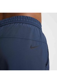 Granatowe szorty sportowe z elastycznym pasem, kieszenią boczną oraz czarnym logo Nike wyszytym z tyłu. Gładki, lekki materiał.