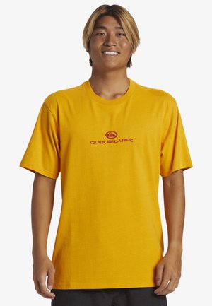 T-shirt giallo a maniche corte realizzato in cotone. Presenta una stampa del logo rosso sul davanti, colletto rotondo e design rilassato.
