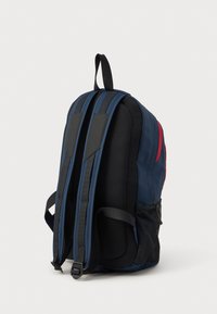 Námořní batoh s černou síťovinou, polstrovanými ramenními popruhy, boční kapsou a červenými akcenty. Obsahuje horní rukojeť pro snadné přenášení.