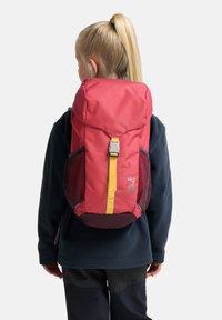 Rucksack in Rot mit gelben Schnallen, seitlichen Netzfächern und runder Oberseite. Hergestellt aus strapazierfähigem Material und mit einem Logo auf der Vorderseite.