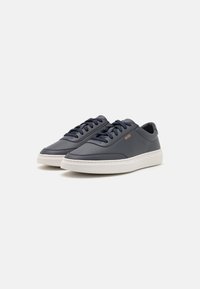 Navy blue leather sneakers with flat laces, white rubber soles, and branded detail on the side. Sleek silhouette with smooth texture.