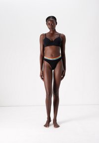 Juodas bevielis liemenukas ir bikini su daugiakolorėmis dryžuotomis juostelėmis. Medžiaga atrodo lygi, su švariu, minimalistiniu dizainu.