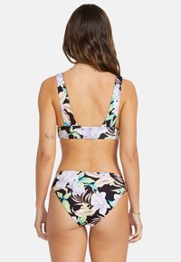 Blommig bikini set med svart bakgrund, prydd med stora ljusa blommor. Toppen har breda axelband och låg rygg; byxorna är högmidjade.