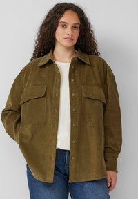 Olijfgroene corduroy overhemd met lange mouwen, twee borstzakken en knoopsluiting aan de voorkant. Relaxte pasvorm, gestructureerd materiaal en effen kleur.