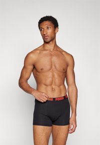 Black boxer briefs with a snug fit and elastic waistband featuring a red Puma logo. Simple design, smooth texture, no additional patterns.