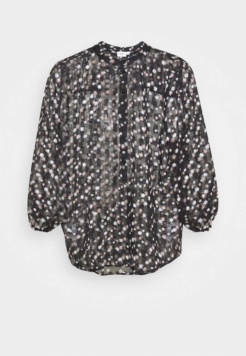 Blusa nera trasparente con motivi a stellina bianchi e rosa chiaro, maniche lunghe a sbuffo, scollatura tonda e patta di bottoni frontale.