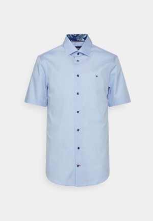 Lichtblauwe, kortgeknipte shirt van katoen. Voorzien van een knoopsluiting aan de voorkant, zwarte knopen en een gestikte kraagvoering. Klein logo op de borst.