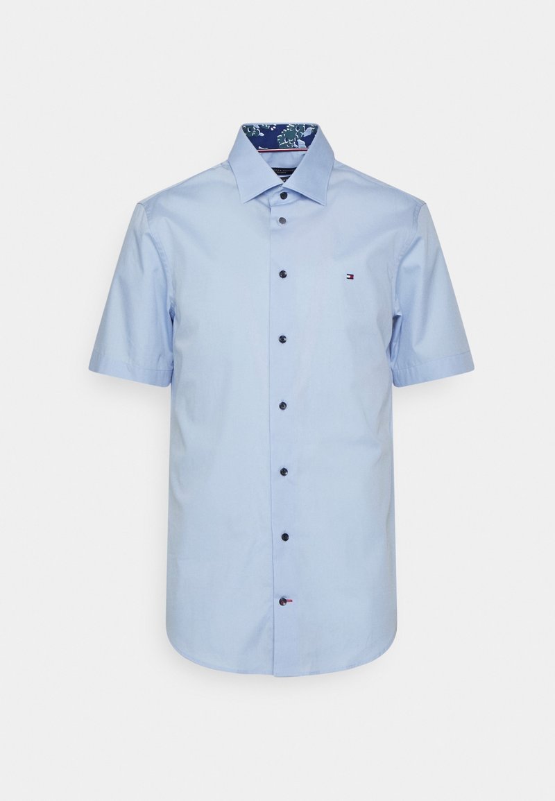 Camicia azzurro chiaro a maniche corte in cotone. Presenta una chiusura con bottoni, bottoni neri e un colletto con fodera a motivi. Piccolo logo sul petto.