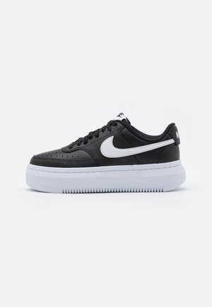 Czarny skórzany sneaker Nike z białym logo swoosh, czarnymi sznurówkami i grubą białą podeszwą na jednolitym białym tle.