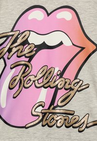 Sivi materijal s emblemom jezika u ružičastoj i bijeloj boji, obrubljenim crnom bojom. Zlatni šljokasti natpis "The Rolling Stones" u kurzivu.