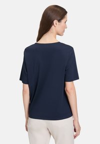 Marineblå T-shirt med kortærmer, rund halsudskæring, blødt stof, løs pasform og minimalistisk design, uden bemærkelsesværdige mønstre eller accenter.