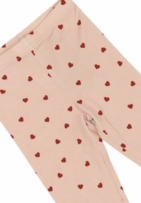 Leggings u svijetlo ružičastom materijalu s mekim teksturom, s uzorkom malih crvenih srca ravnomjerno rasprostranjenih po površini.