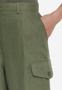 Khakis i en strukturerad tygkvalitet, med en sidoficka med knäppning och en bältesöljare i midjan. Rent snitt och skräddarsydd passform.