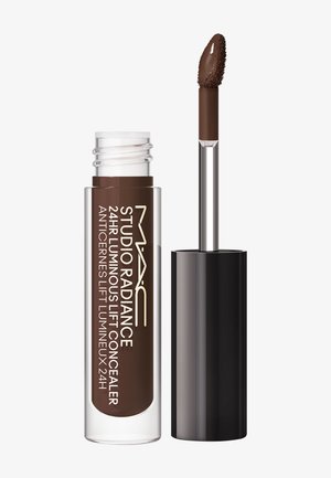 Correcteur MAC Studio Radiance 24 heures effet lift lumineux avec applicateur baguette montrant un produit liquide marron foncé sur le pinceau.