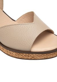 Beżowe skórzane sandały z szerokim krzyżującym się paskiem, otwartym noskiem oraz teksturowaną wplecioną podeszwą platformową dla zwiększonej wysokości i przyczepności.